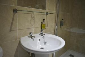 La salle de bains est pourvue d'un lavabo blanc et d'une douche. dans l'établissement Stallingborough Grange Hotel, à Stallingborough