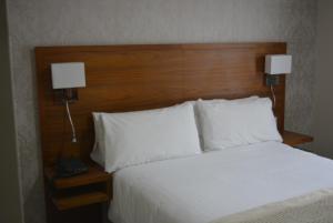 1 dormitorio con 1 cama con almohadas blancas y 2 lámparas en Stallingborough Grange Hotel en Stallingborough