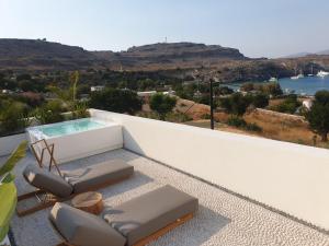 a balcony with two chairs and a swimming pool at AF Lindia Nature Design Hotel in Lindos