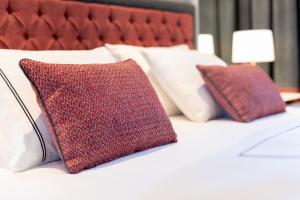 a bed with red and white pillows on it at Motif Hotel Çeşme in Çeşme