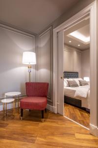a bedroom with a bed and a red chair and a table at Motif Hotel Çeşme in Çeşme