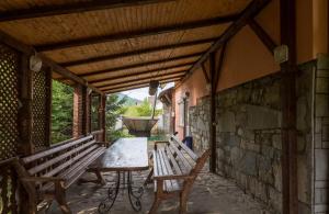 porche con bancos, mesa y pared de piedra en Cottage Persona Lux en Slavske