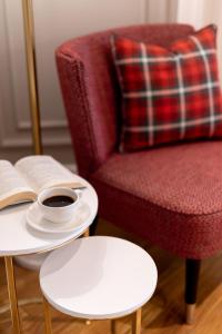 a cup of coffee and a book on a table next to a chair at Motif Hotel Çeşme in Çeşme