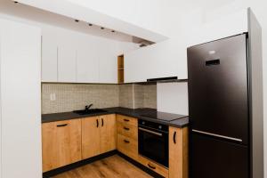 a kitchen with a black refrigerator and wooden cabinets at Homeland Apartments VIVA in Cluj-Napoca