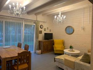 a living room with a table and a yellow chair at Māja pie Ziedu laivas in Plieņciems