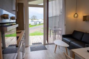 ein Wohnzimmer mit einem Sofa und einer Tür zu einer Terrasse in der Unterkunft Asaa Camping & Cottages in Aså