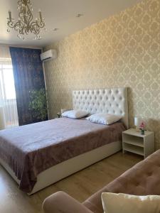 a bedroom with a large bed and a couch at Apartments on Aviatorov 10 in Abakan