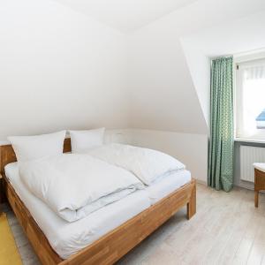 Schlafzimmer mit einem Bett mit weißer Bettwäsche und einem Fenster in der Unterkunft Wohnung Ost in Westerland
