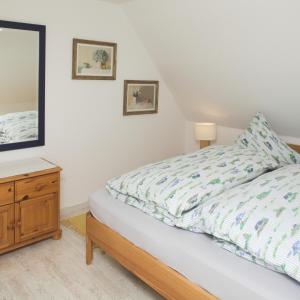 Schlafzimmer mit einem Bett, einer Kommode und einem Spiegel in der Unterkunft Wohnung Ost in Westerland