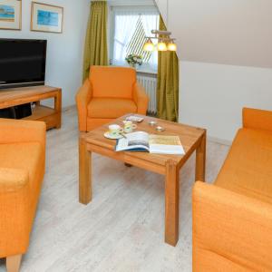 a living room with orange chairs and a coffee table at Wohnung West in Westerland