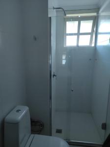 a white bathroom with a shower and a toilet at Duplex em Gramado in Gramado