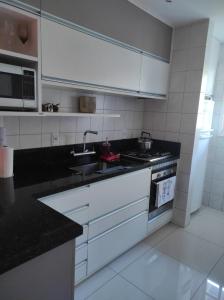 a kitchen with white appliances and black counter tops at Duplex em Gramado in Gramado +12 photos