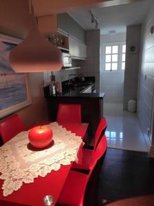 a red dining room table with red chairs and a kitchen at Duplex em Gramado in Gramado