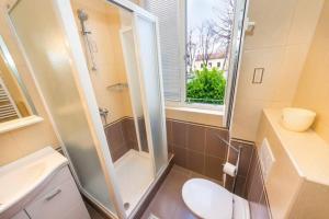 een badkamer met een douche, een toilet en een raam bij Sea Organ Apartment Zadar in Zadar