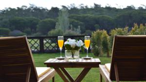 deux verres de vin et de fleurs sur une table en bois dans l'établissement Quinta Formosa Villa, à Quinta do Lago