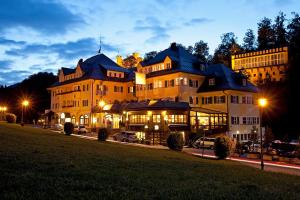 duży budynek w nocy z samochodami zaparkowanymi przed nim w obiekcie Hotel Müller w mieście Hohenschwangau