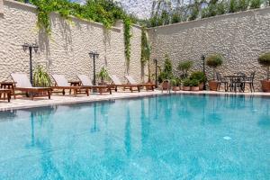 a large swimming pool with chairs and tables and a wall at Motif Hotel Çeşme in Çeşme