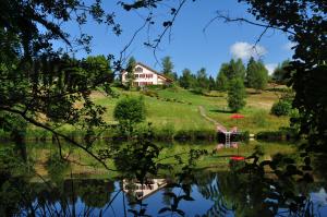 a house sitting on top of a hill next to a lake at "Chambre Merisier" dans une ferme avec étang privé au coeur de la région des mille étangs, Faucogney-et-La-Mer in Faucogney-et-la-Mer