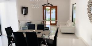 a dining room with a glass table and black chairs at White House Mansion in San Felipe de Puerto Plata