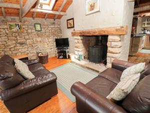 a living room with leather furniture and a stone fireplace at The Granary in Morpeth