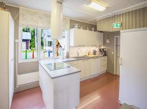 a kitchen with white cabinets and a large window at Yksityinen järvenrantakohde ryhmille sauna, luonto ja oma rauha in Jämsä