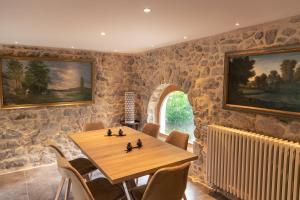 comedor con paredes de piedra, mesa de madera y sillas en La chapelle moulin traversée par l'eau jacuzzi piscine classé 5 étoiles, en Bourg-Argental