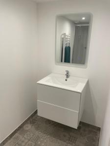 a white bathroom with a sink and a mirror at duplex cosy au cœur de Royat in Royat