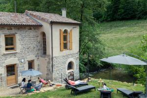 un grupo de personas sentadas fuera de una casa en La chapelle moulin traversée par l'eau jacuzzi piscine classé 5 étoiles, en Bourg-Argental