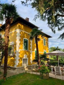 a yellow house with green shutters and palm trees at apartman Cedra in Izola