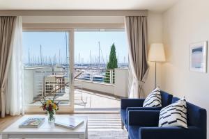 a living room with a blue couch and a large window at Marina di Scarlino Resort in Puntone di Scarlino