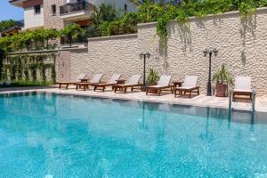 a large swimming pool with chairs and a building at Motif Hotel Çeşme in Çeşme