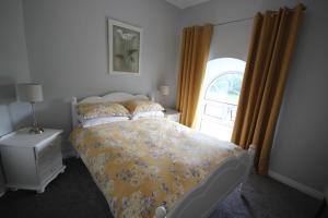 a bedroom with a bed with a yellow bedspread and a window at Mullarts Church -The Glenann Apartment in Knocknacarry