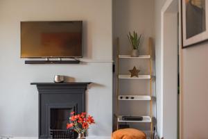 a living room with a fireplace with a tv above it at Pitch Perfect by Bloom Stays in Canterbury