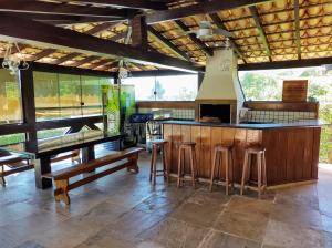 a kitchen with a bar with stools and tables at Casa em Escarpas do Lago Ótimo Preço, Aconchegante, Área bem Ampla e Excelente Localização in Capitólio