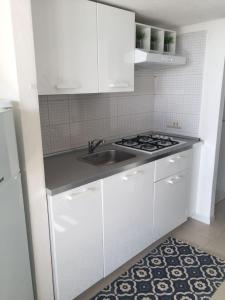 uma cozinha branca com um lavatório e um fogão em Casa Penny em Capo Sperone