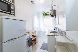a white kitchen with a sink and a refrigerator at Sunny Boho Chic West Hollywood Flat! in Los Angeles