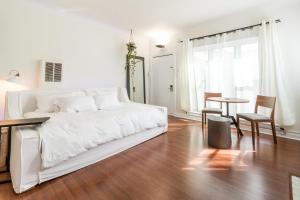 a white bedroom with a white bed and a table at Sunny Boho Chic West Hollywood Flat! in Los Angeles