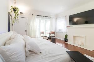 a bedroom with a white bed and a fireplace at Sunny Boho Chic West Hollywood Flat! in Los Angeles