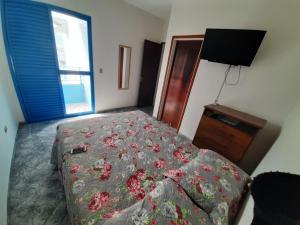 Schlafzimmer mit einem Bett, einem TV und einem Fenster in der Unterkunft Lindo Apto Praia Martin de Sá em Condomínio com Piscina, Estacionamento, WI-FI 150mbps,PERTO DO MAR!!! in Caraguatatuba