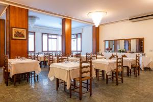 une salle à manger avec des tables et des chaises blanches dans l'établissement Hotel Terme Posta Padova HOTEL RC12, à Abano Terme