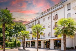 a large white building with palm trees in front of it at Hotel Terme Posta Padova HOTEL RC12 in Abano Terme