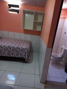 a bedroom with a bed and a mirror and a toilet at Pousada Kaka in Teresina