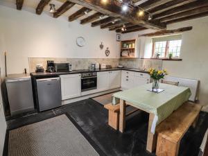 a kitchen with white cabinets and a table in it at Ty Tabitha Wynne in Caerwys
