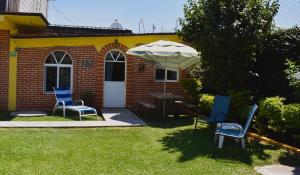 a patio with chairs and a table and an umbrella at Hotel y Cabañas Quinta Los Cipreses in Atlatlahucan