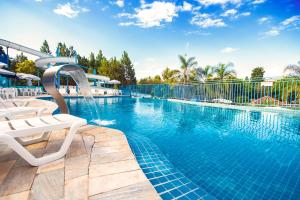 a swimming pool with two chairs and a water slide at Hotel Vilage Inn All Inclusive Poços de Caldas By Nacional Inn in Poços de Caldas