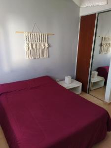 1 dormitorio con cama morada y espejo en departamento catalina en Colón