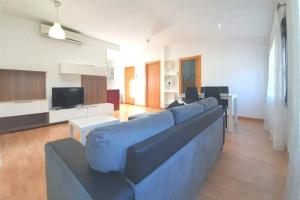 a living room with a blue couch and a tv at Ático en Monzón in Monzón