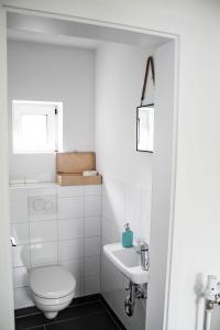 a white bathroom with a toilet and a sink at Ferienwohnung-Heinke-Urlaub-in-Tating-nahe-St-Peter-Ording in Tating