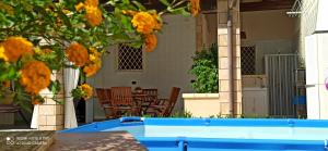 una piscina azul frente a una casa con flores amarillas en GAIA HOUSE, en Alliste