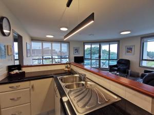 uma cozinha com um lavatório num balcão com janelas em The Anchorage Apartments em Mount Maunganui